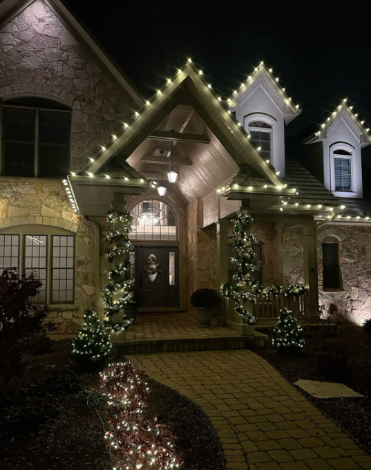 Stone entrance with garland-wrapped columns and roofline lights