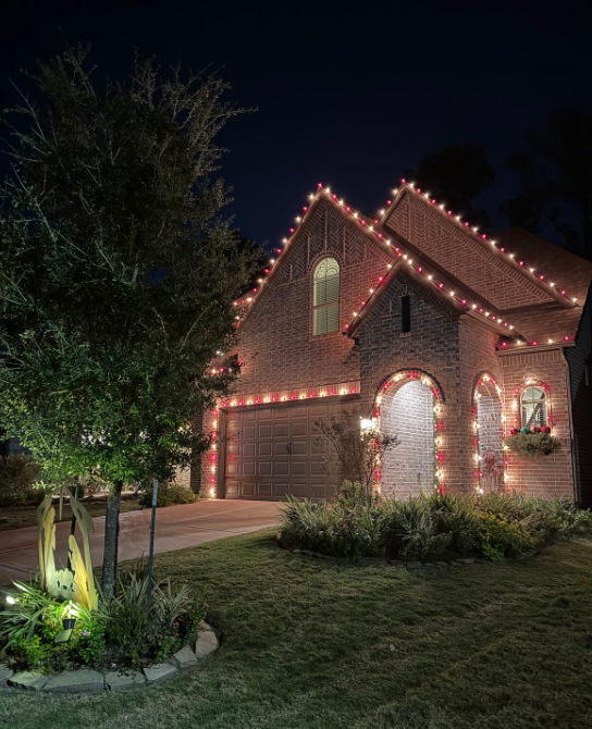 Brick home with roofline and accent holiday lights at night