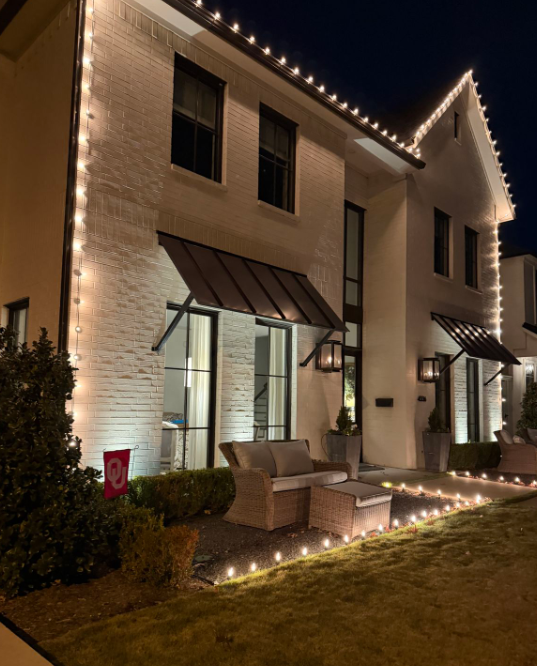 Modern white brick townhouse with warm white roofline lights