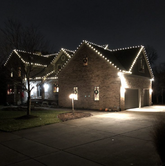 Brick home with roofline string lights and driveway lighting
